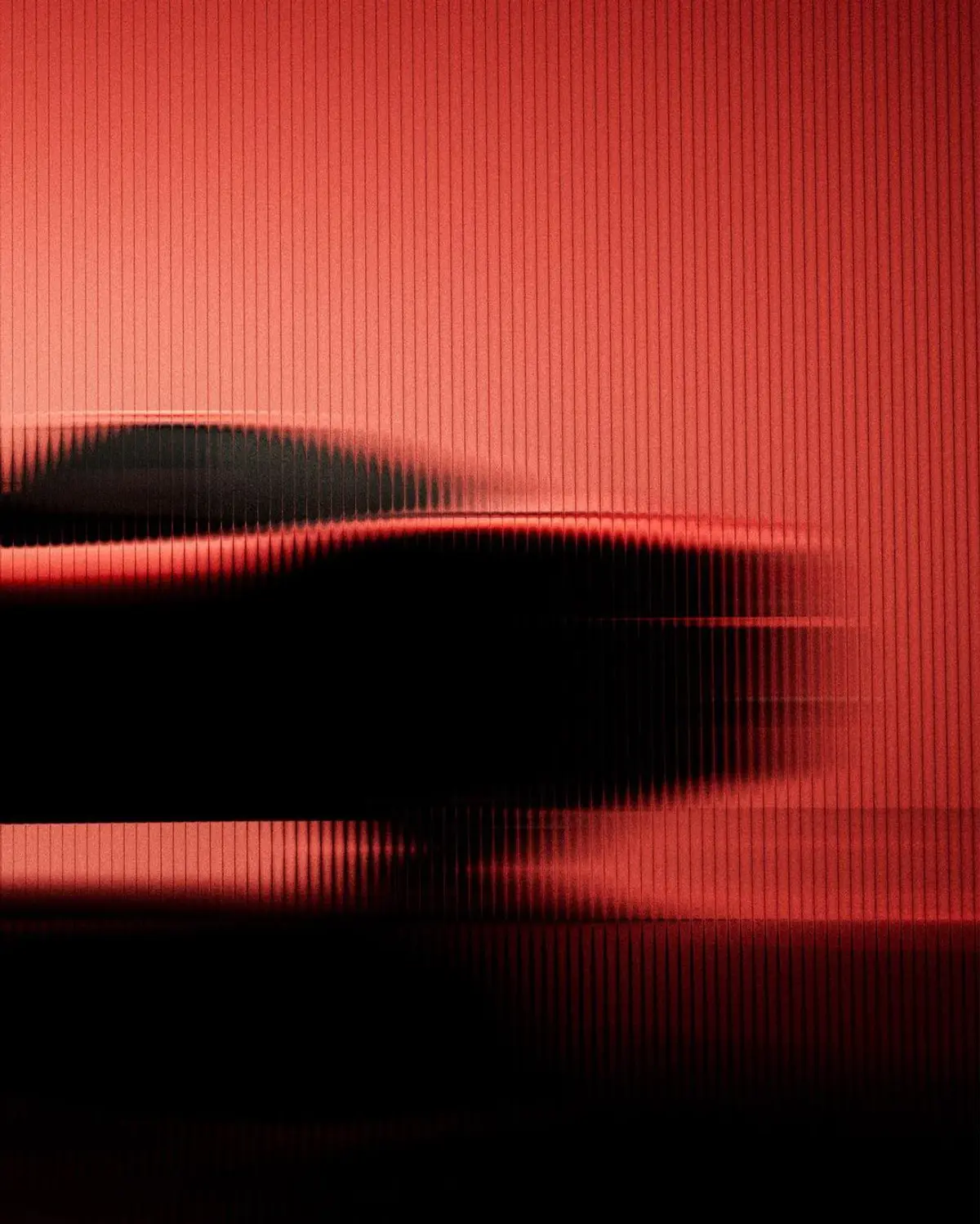 Silueta de un automóvil detrás de un vidrio acanalado rojo